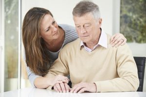 A woman is offering encouragement to an elderly man with Parkinson's disease