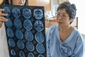 a color photo of a woman doctor reviewing a series of medical head scans with an elderly woman patient 