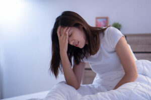 woman with a migraine headache in the morning in bed