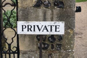 old white wooden sign that says "Private" in bold black letter posted on an old stone gatepost with black iron fittings