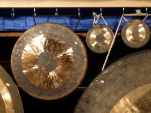 Chinese Chau gongs hanging on hooks on a wooden rack - Image by Hans Braxmeier